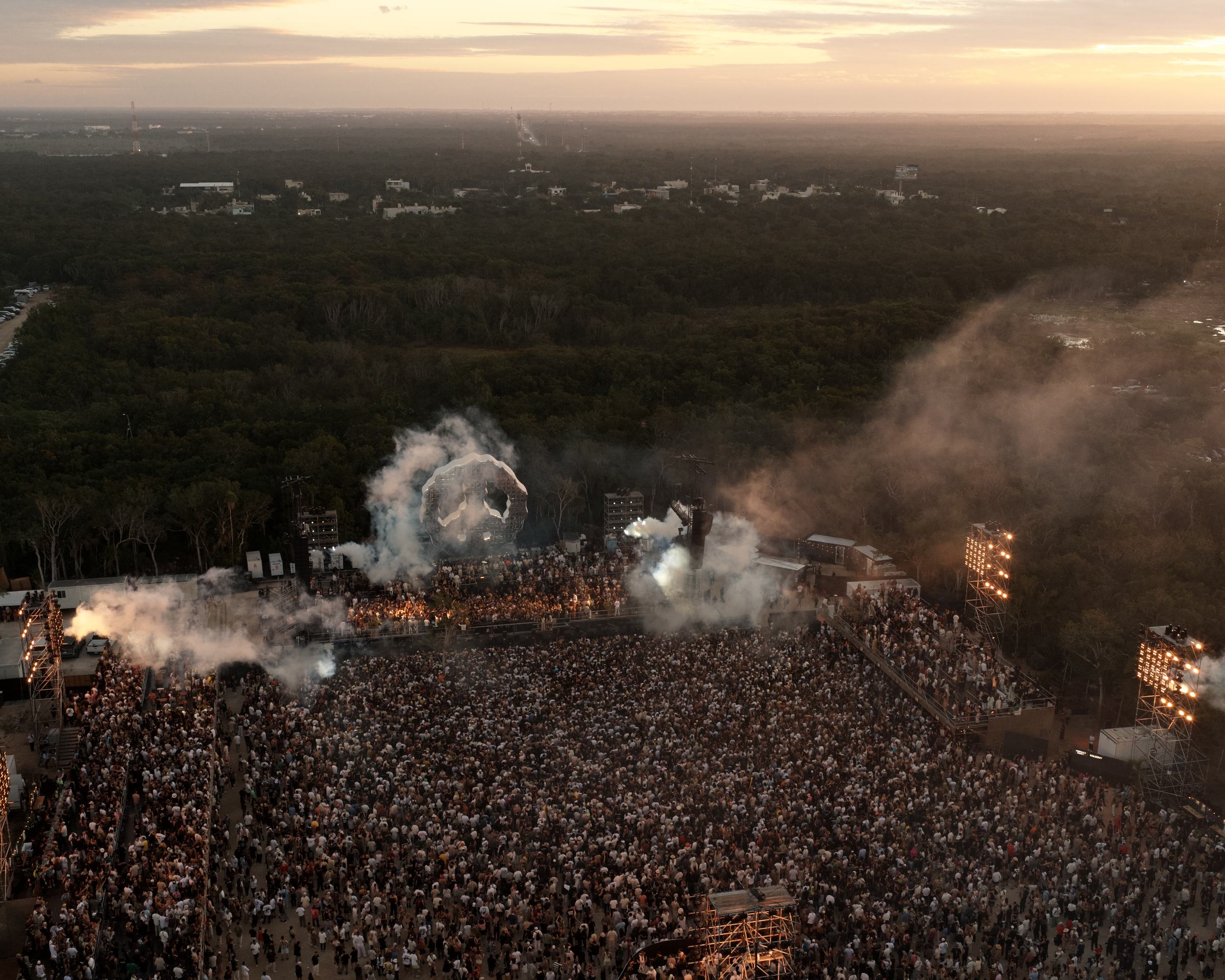 Aerial view of a large-scale live event in the Tulum jungle at sunset